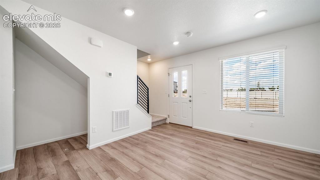 Image 10 of 24: Bright, open living space showcasing wood-finish flooring, recessed ceiling