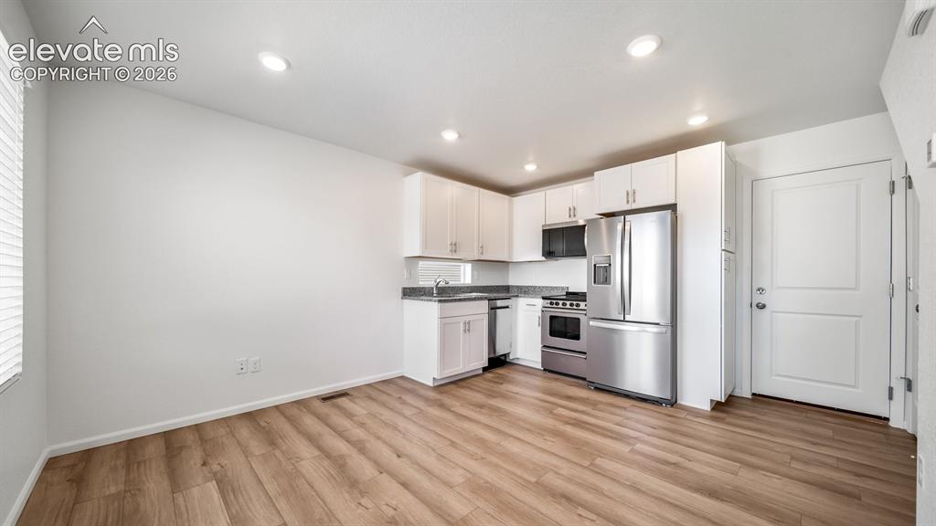Image 12 of 24: Kitchen featuring stainless steel appliances, white cabinetry, and granite