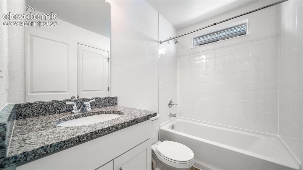 Image 2 of 24: Bathroom featuring a white vanity with a granite-style countertop, undermou