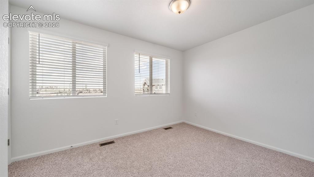 Image 4 of 24: Neutral wall color, two windows with blinds, and a flush mount ceiling ligh