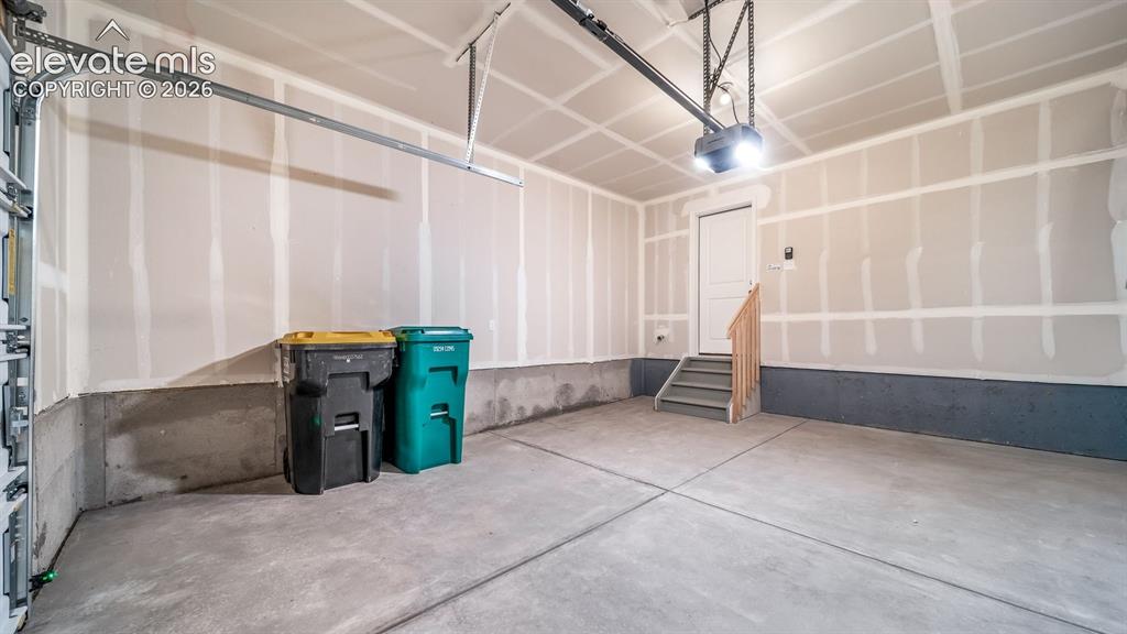 Image 5 of 24: Finished garage interior with a concrete floor, overhead lighting, and inte