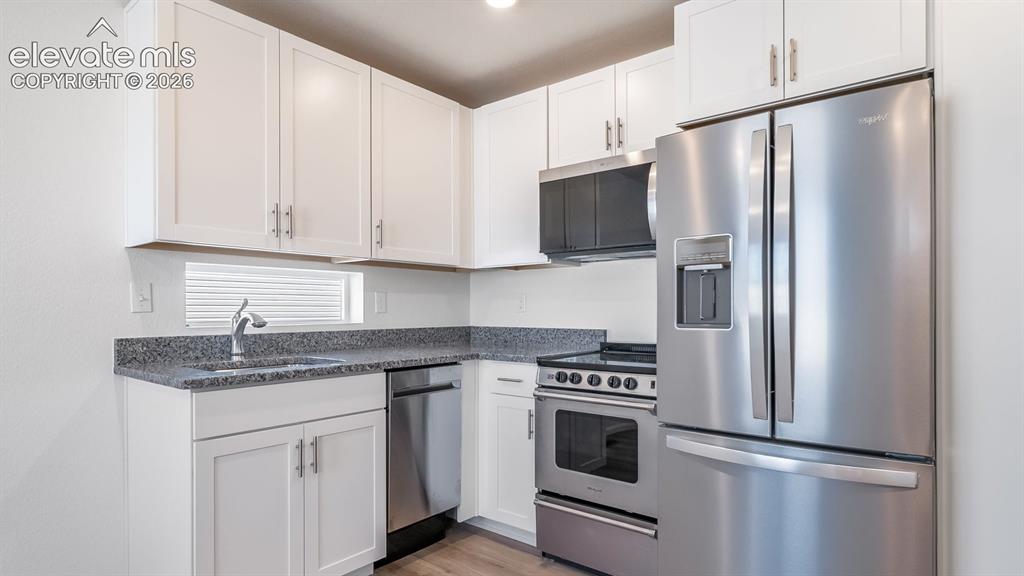 Image 6 of 24: White shaker-style cabinetry with brushed nickel hardware, speckled counter
