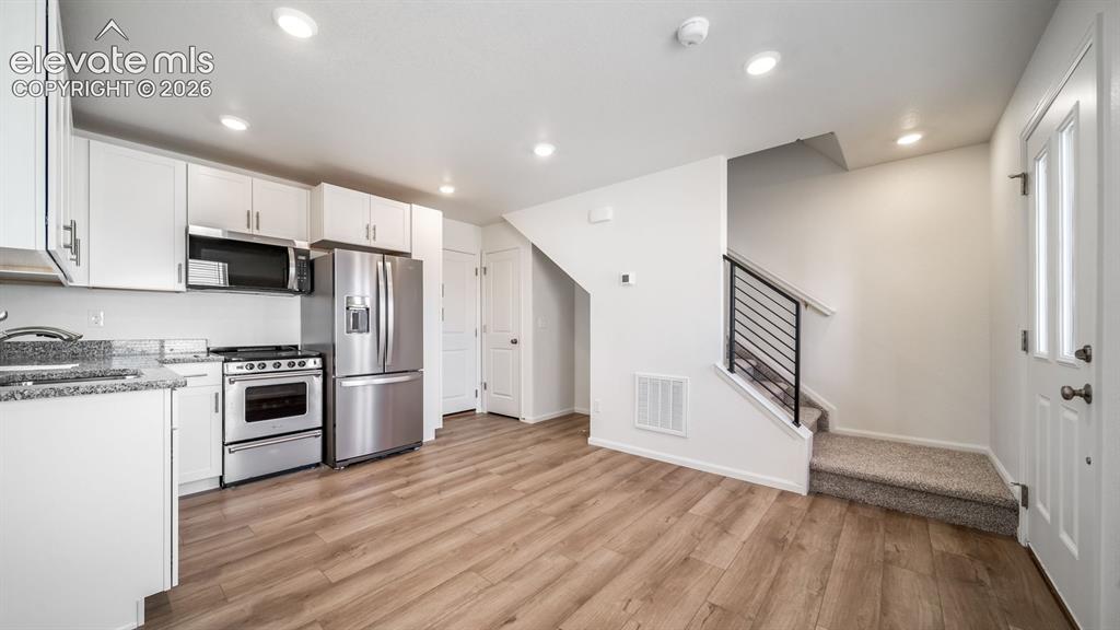 Image 9 of 24: Kitchen featuring white cabinetry, stainless steel appliances, and wood-fin