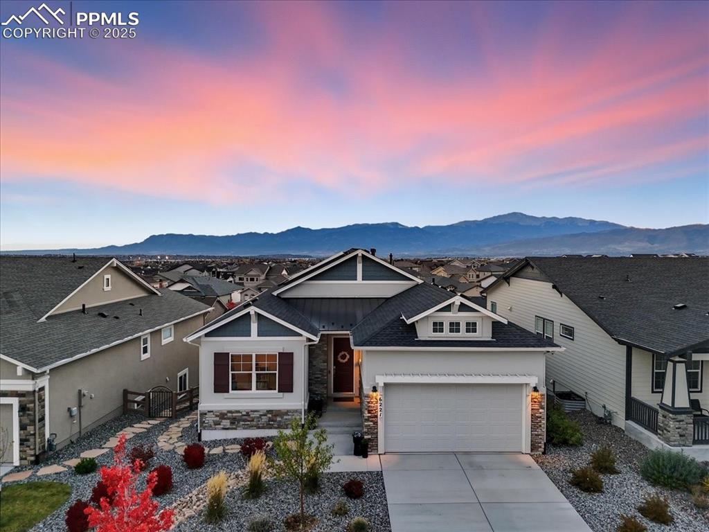 Caption: Craftsman-style house featuring stone siding, concrete driveway, a mountain view, and a garage