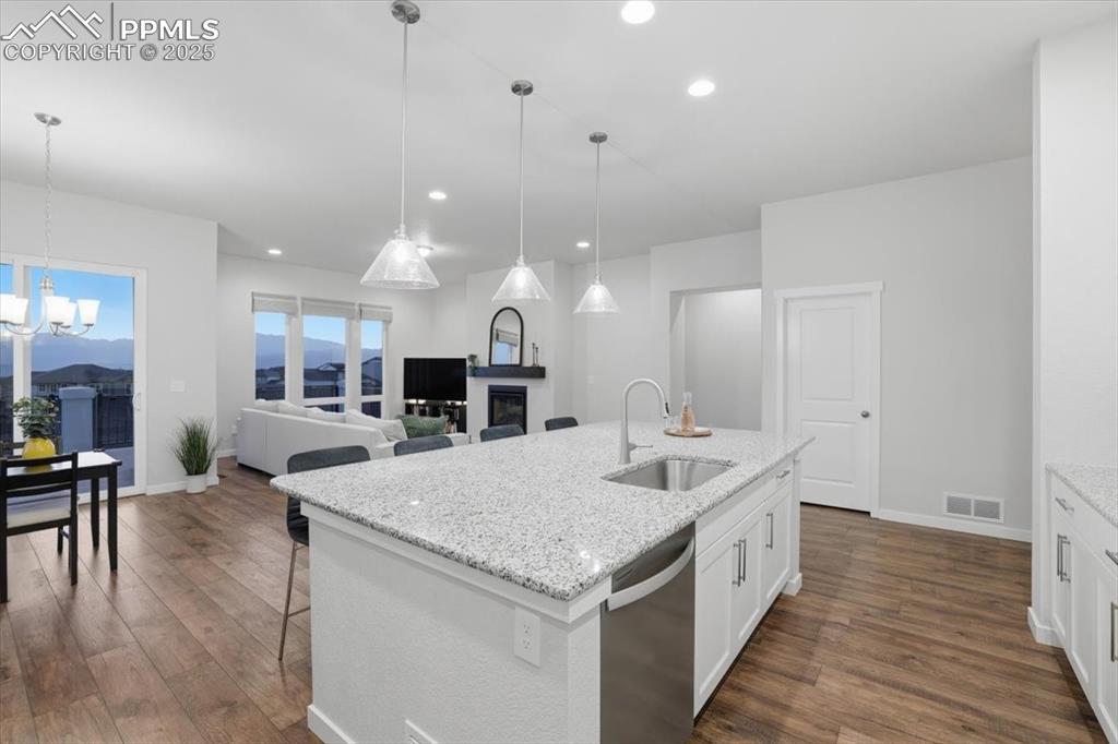 Image 11 of 43: Kitchen with light stone counters, dishwasher, dark wood-style floors, a br