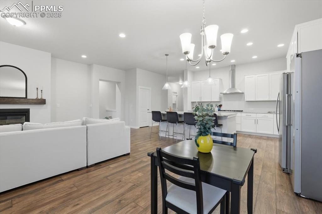 Image 14 of 43: Dining area with dark wood-type flooring, recessed lighting, and a chandeli