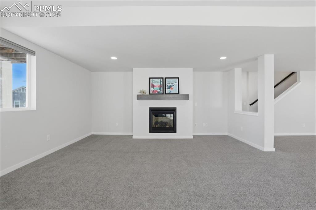Image 34 of 43: Unfurnished living room featuring carpet flooring, a glass covered fireplac
