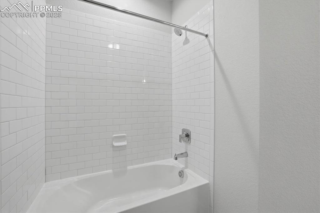 Image 40 of 43: Bathroom featuring shower / washtub combination and a textured wall