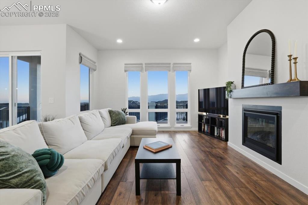 Image 6 of 43: Living area with a glass covered fireplace, dark wood-type flooring, and re