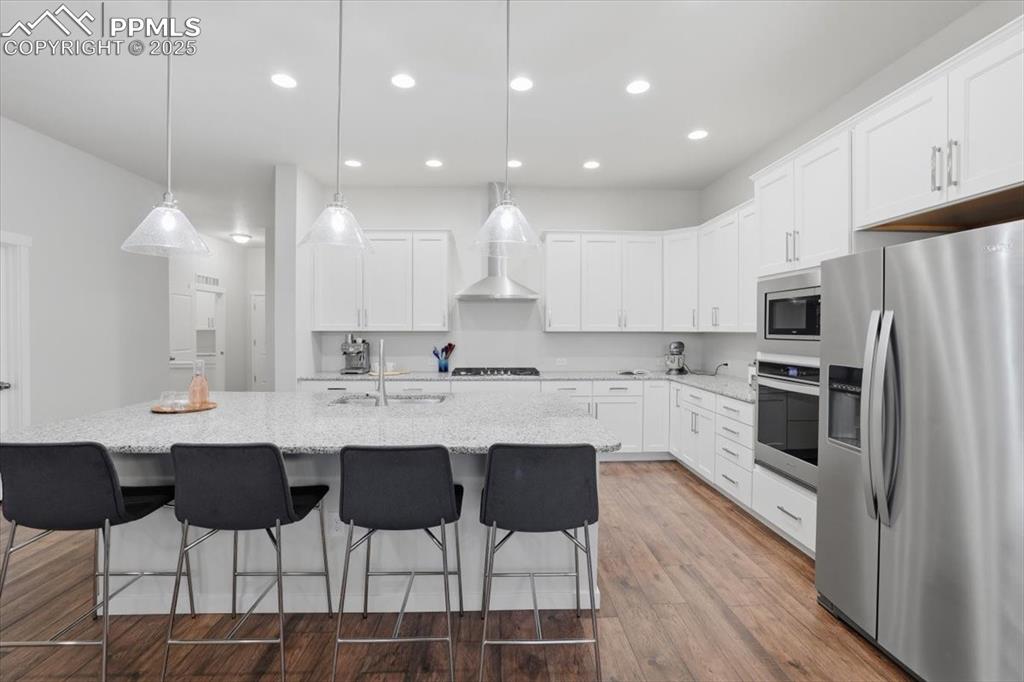 Image 9 of 43: Kitchen with appliances with stainless steel finishes, dark wood-style floo