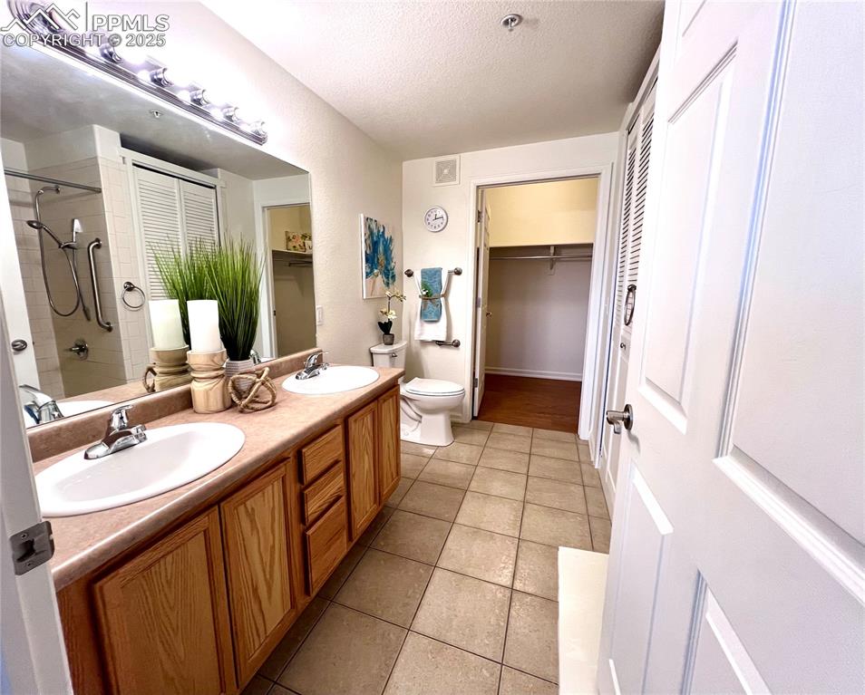 Image 15 of 30: Bathroom with toilet, tile, and dual bowl vanity