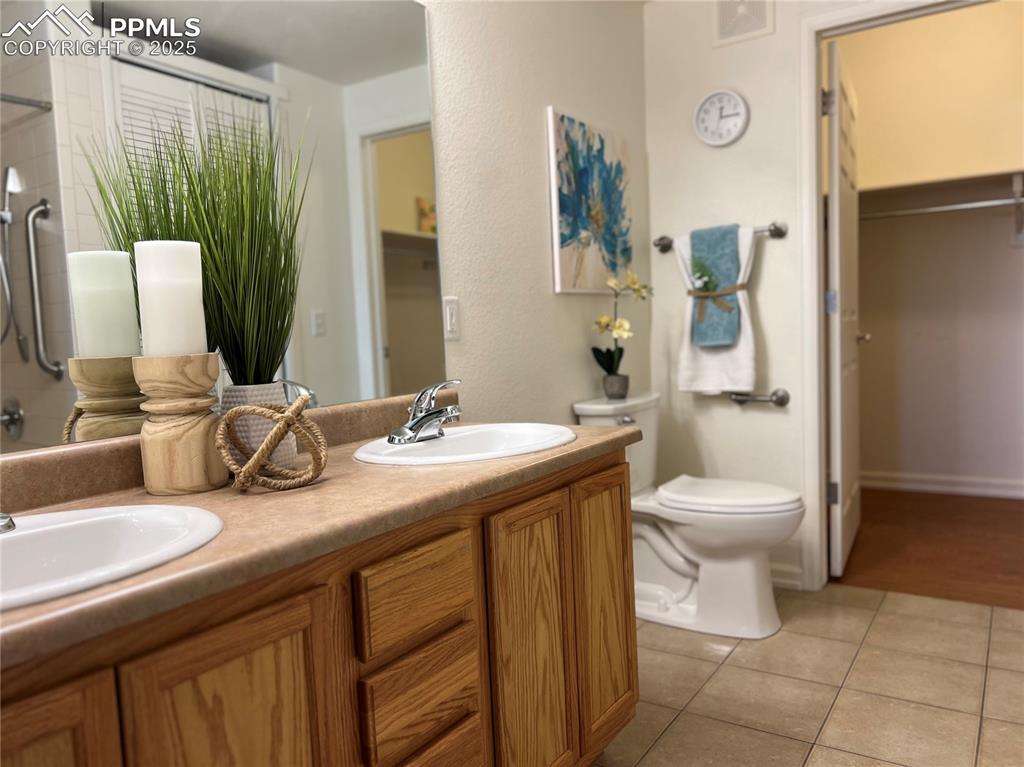 Image 16 of 30: Bathroom featuring dual vanity, large shower and linen closet