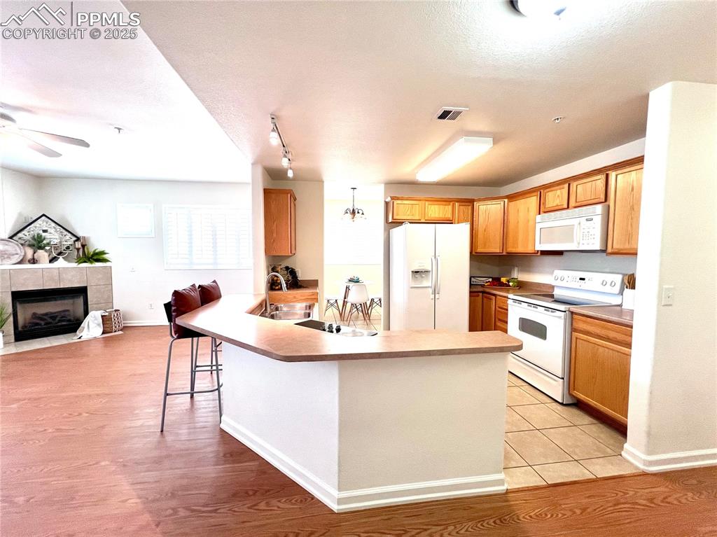 Image 5 of 30: Kitchen with white appliances, a kitchen breakfast bar, extra cooktop, grea