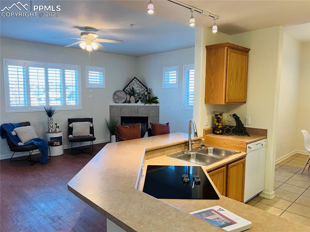 Image 8 of 30: Kitchen with white dishwasher, sink, a tiled fireplace, and a wealth of nat