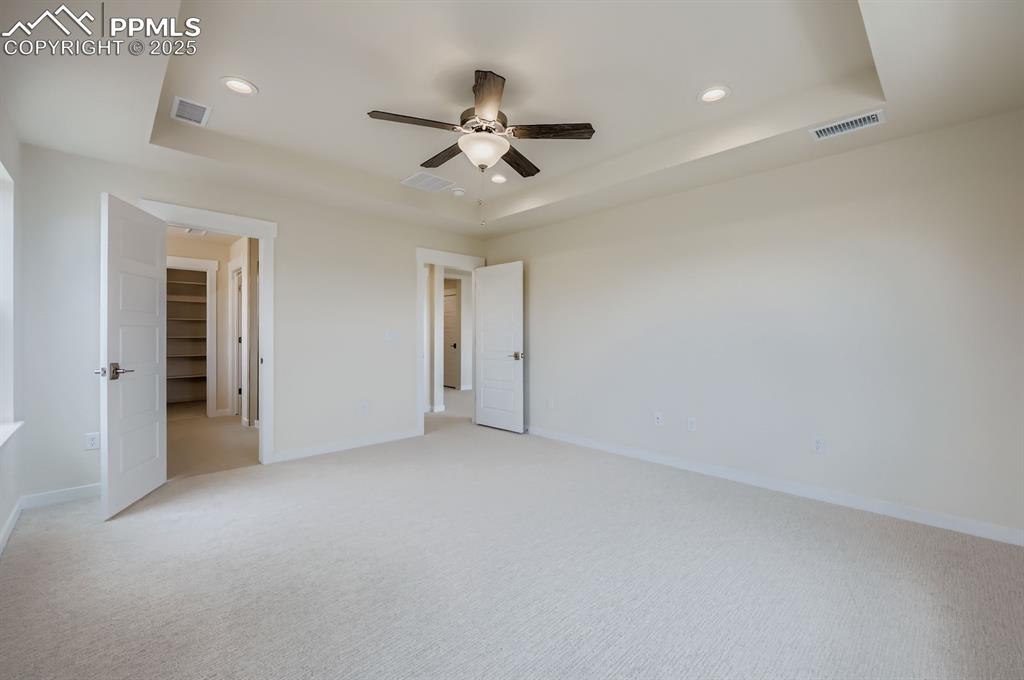 Image 14 of 28: Unfurnished bedroom with a tray ceiling, recessed lighting, light carpet, a
