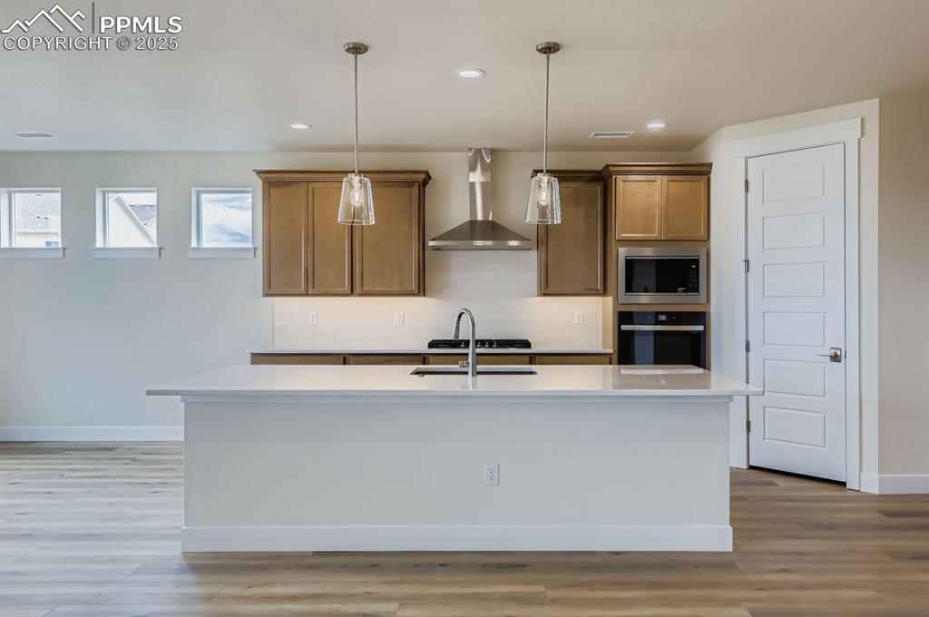 Image 9 of 28: Kitchen featuring wall chimney exhaust hood, stainless steel appliances, de