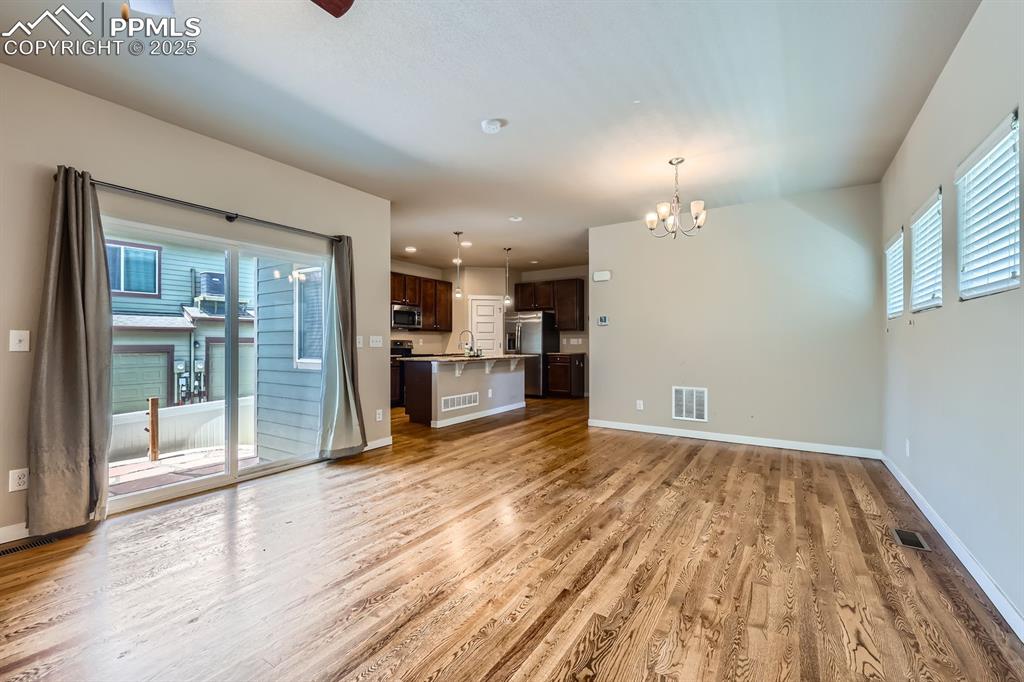 Image 11 of 27: Unfurnished living room featuring light wood finished floors, a chandelier,
