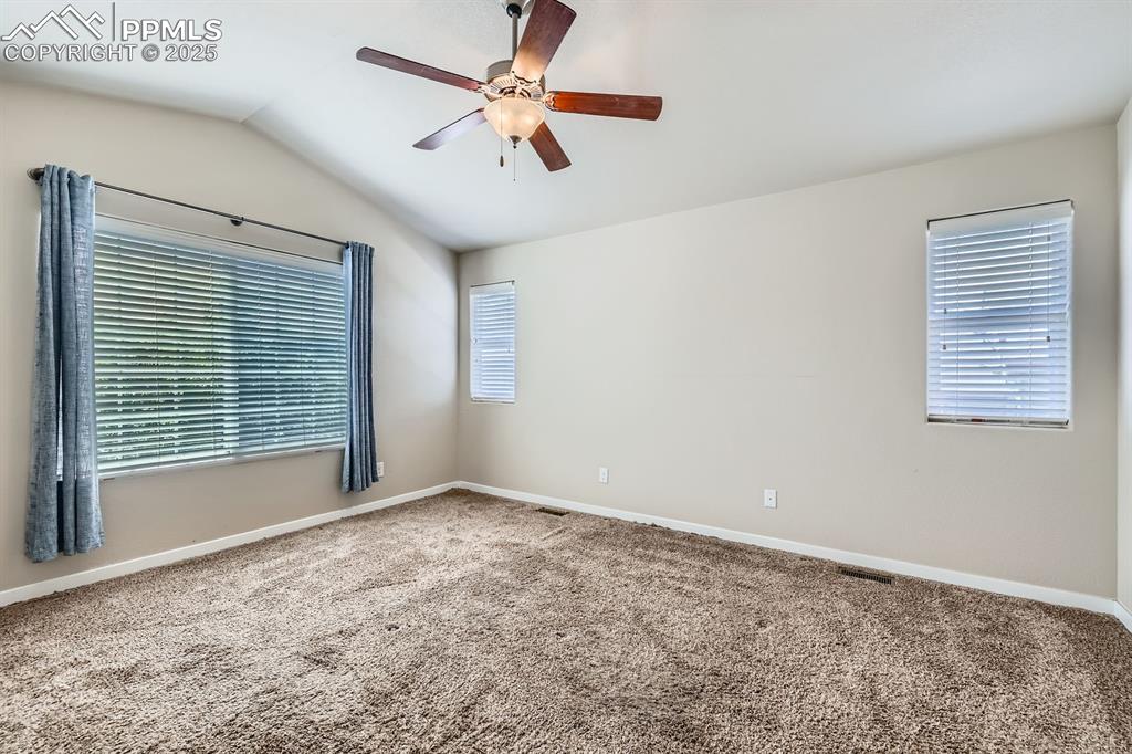Image 13 of 27: Empty room with a ceiling fan, carpet flooring, lofted ceiling, and healthy