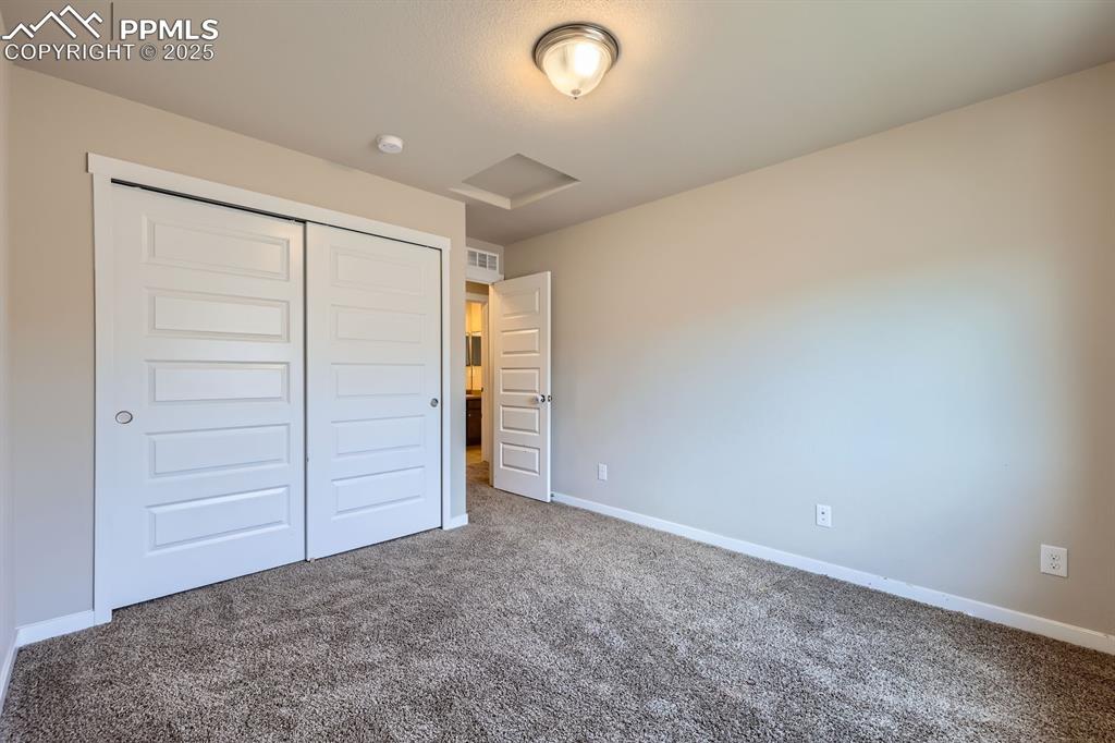 Image 18 of 27: Unfurnished bedroom with carpet floors, a closet, and attic access