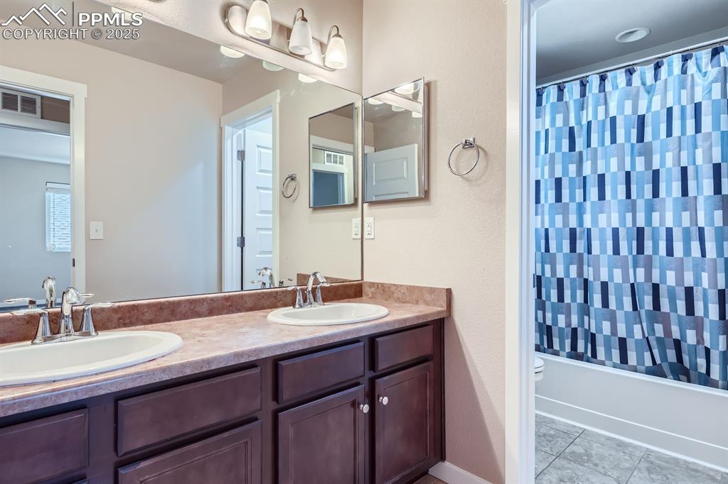 Image 21 of 27: Bathroom with double vanity, shower / bath combo, and tile patterned floori