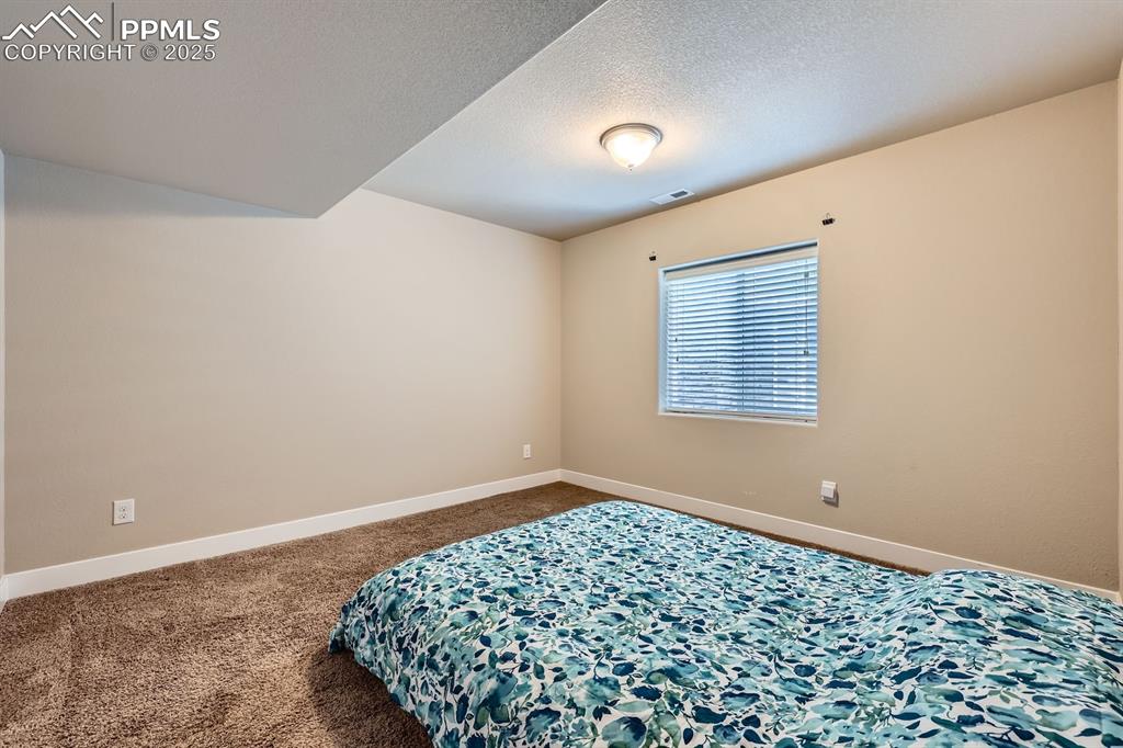 Image 25 of 27: Carpeted bedroom with baseboards and a textured ceiling