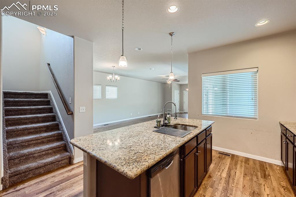 Image 9 of 27: Kitchen with stainless steel dishwasher, light wood finished floors, pendan