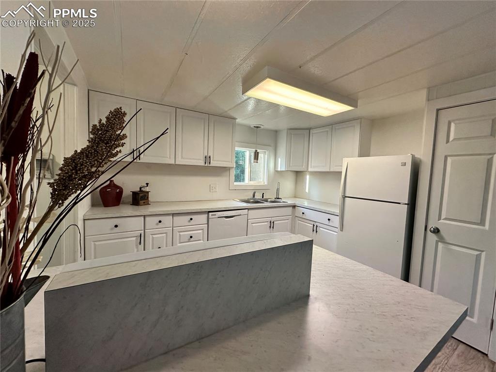 Image 18 of 36: Kitchen with light countertops, white appliances, and white cabinetry