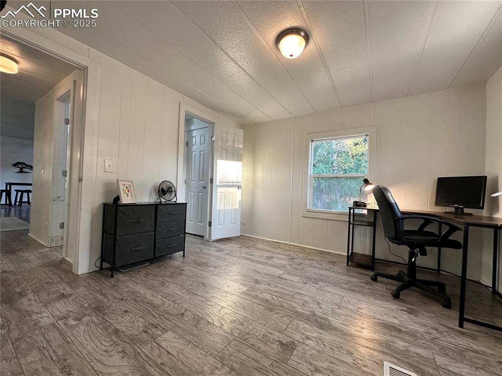 Image 28 of 36: Home office with wood finished floors and wooden walls