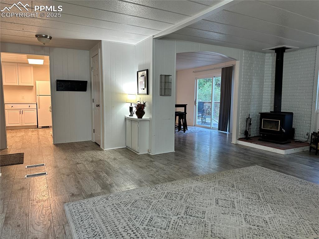 Image 30 of 36: Unfurnished living room with a wood stove, light wood-style floors, wood wa