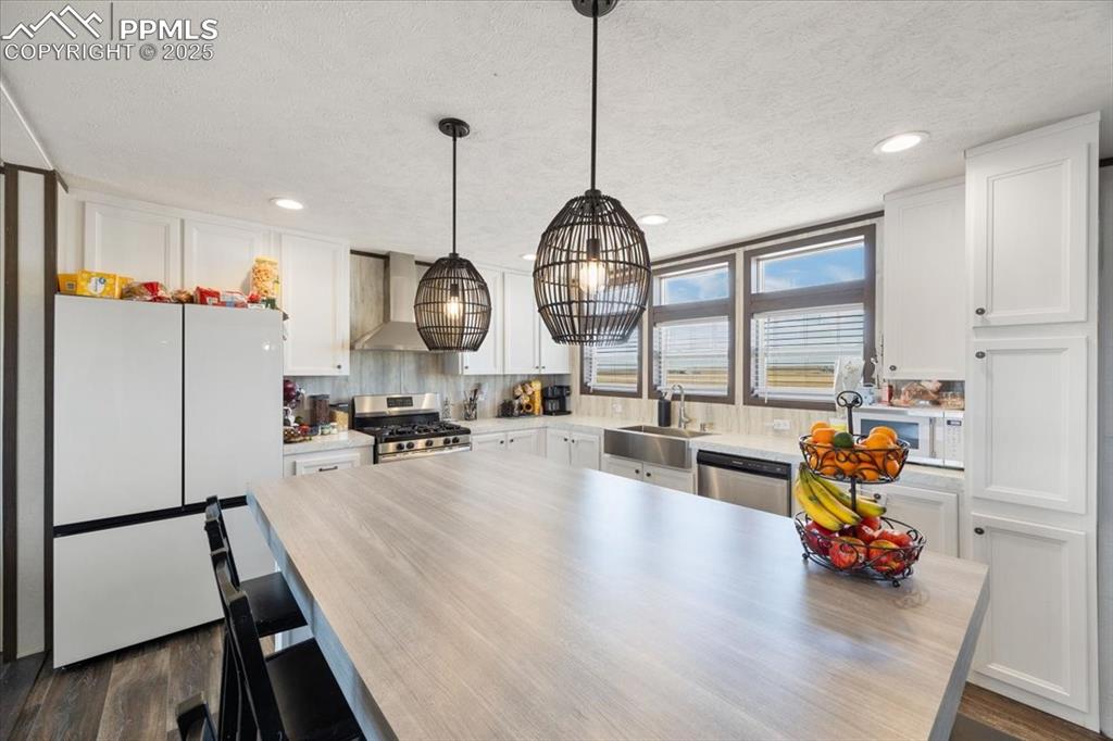Image 12 of 40: Kitchen featuring appliances with stainless steel finishes, white cabinetry