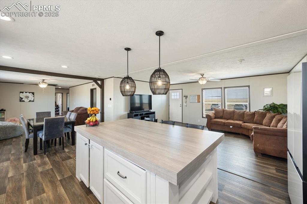Image 13 of 40: Kitchen featuring open floor plan, ceiling fan, white cabinetry, light coun