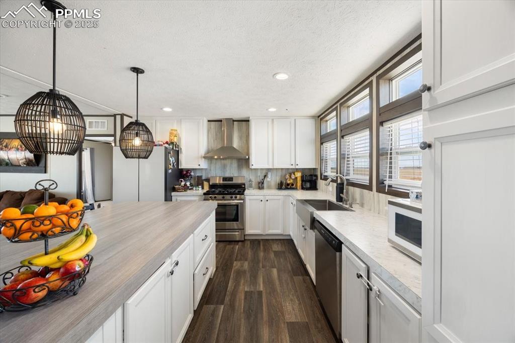 Image 14 of 40: Kitchen with stainless steel appliances, light countertops, dark wood-style