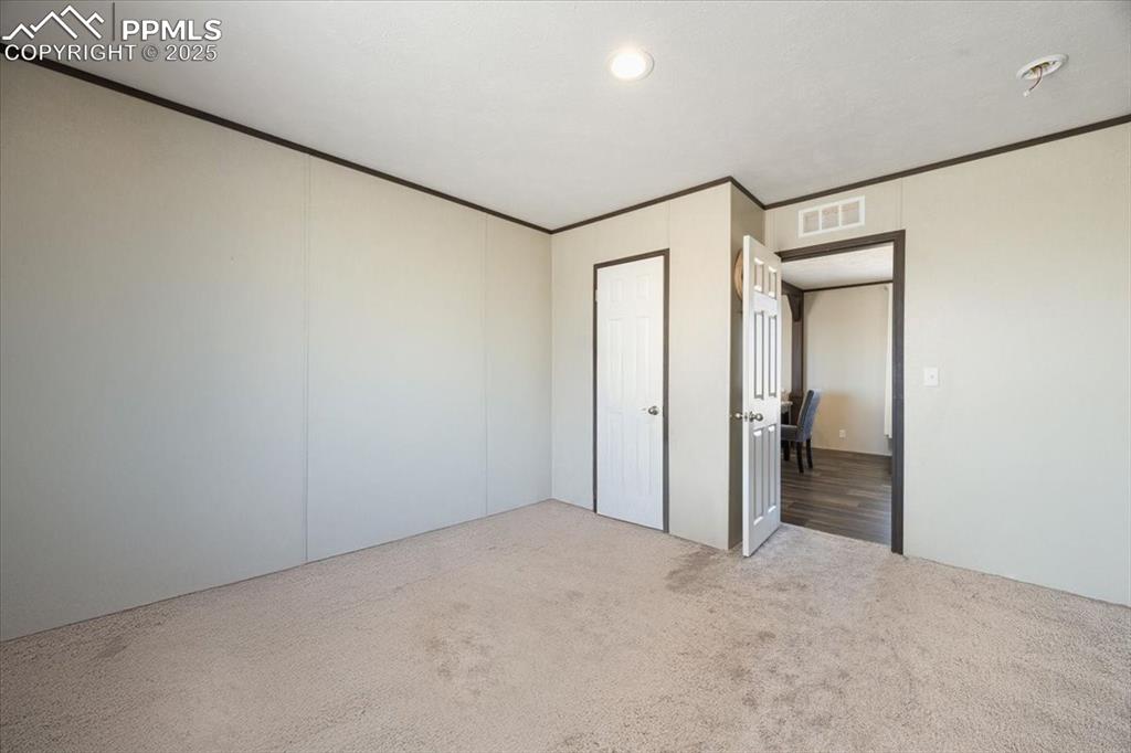 Image 18 of 40: Unfurnished bedroom with ornamental molding, carpet floors, a closet, and r