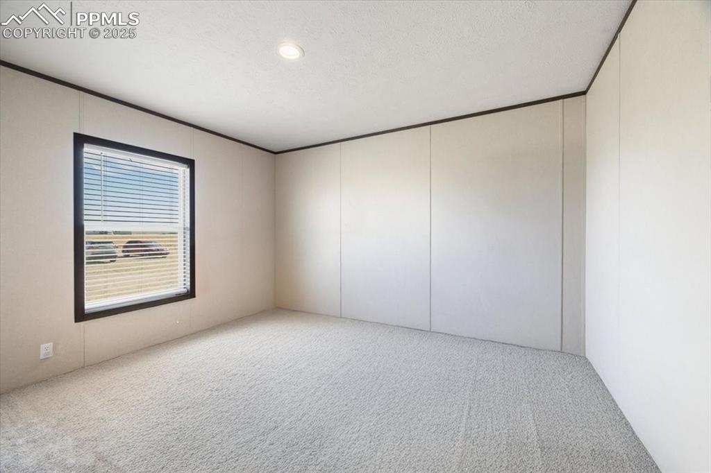 Image 28 of 40: Empty room featuring carpet floors, a textured ceiling, a decorative wall, 