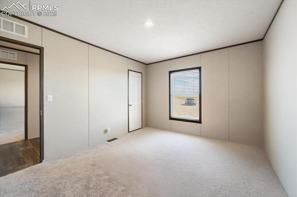 Image 29 of 40: Unfurnished bedroom with carpet flooring, ornamental molding, and a texture