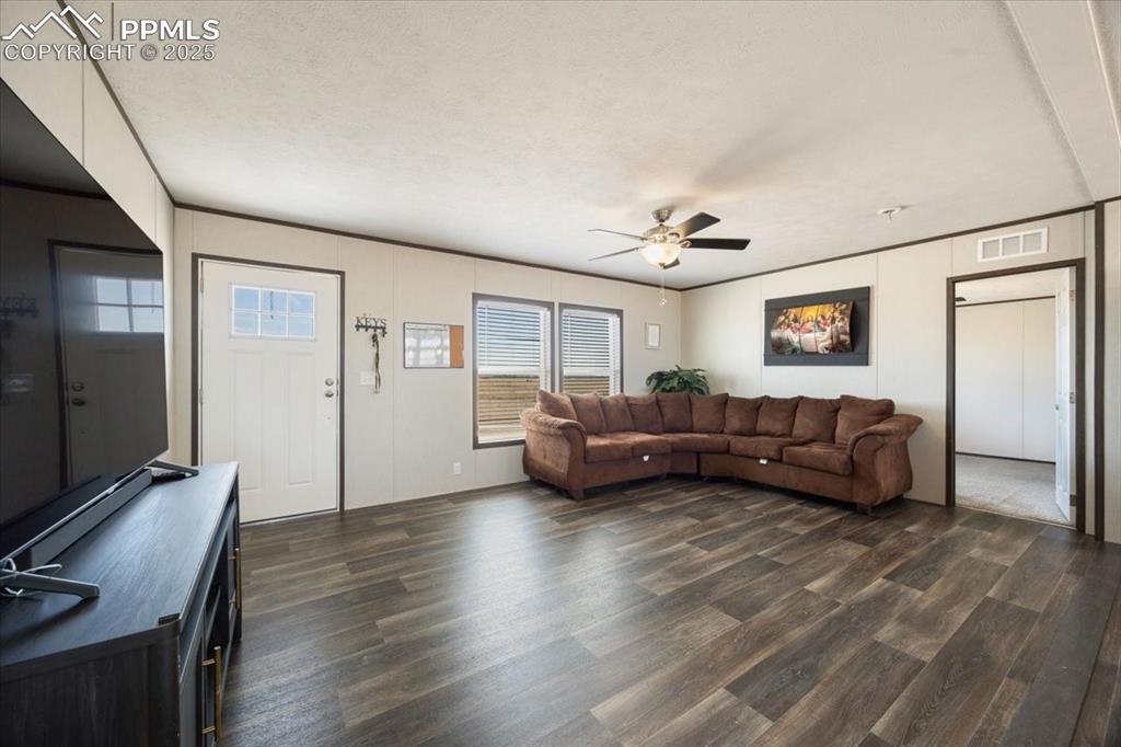 Image 6 of 40: Living area with dark wood-style flooring, ceiling fan, and a textured ceil