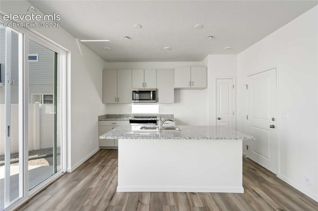 Image 7 of 24: Kitchen featuring a central island with an integrated sink, light-toned cab