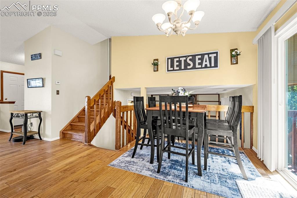 Image 12 of 37: Dining room with a chandelier, light wood-style floors, vaulted ceiling, st