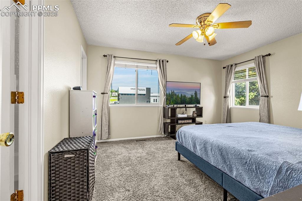Image 20 of 37: Carpeted bedroom featuring ceiling fan and a textured ceiling