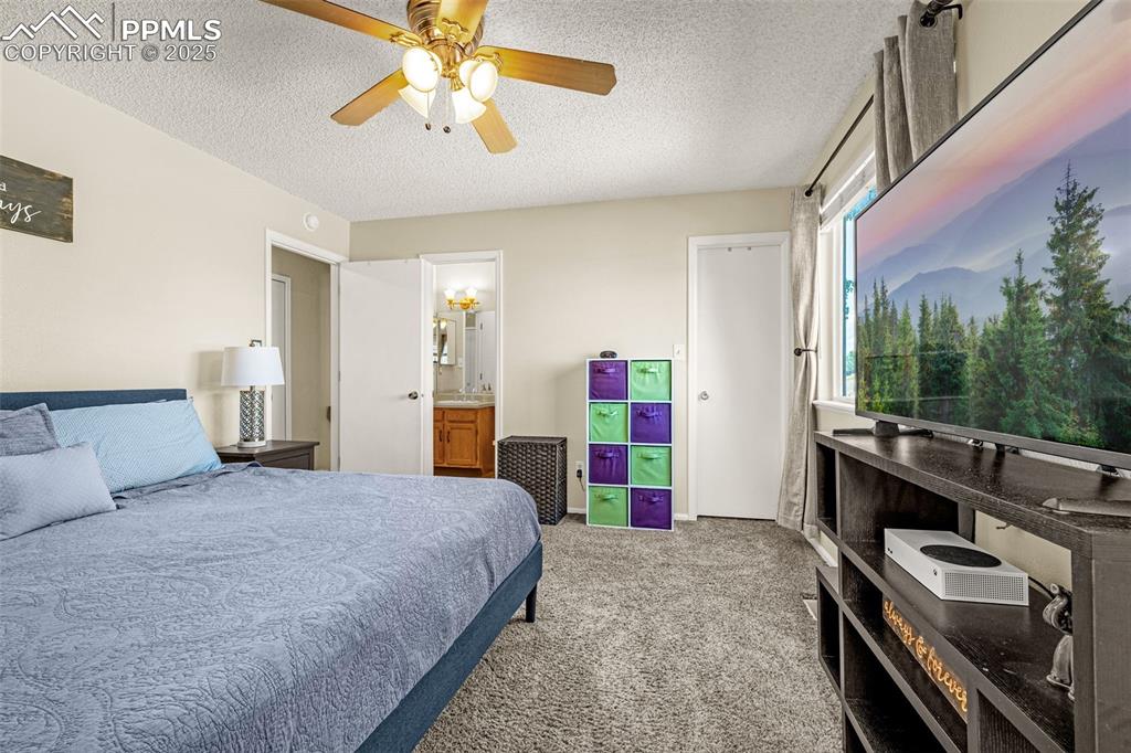 Image 21 of 37: Bedroom with a textured ceiling, light colored carpet, a ceiling fan, and c