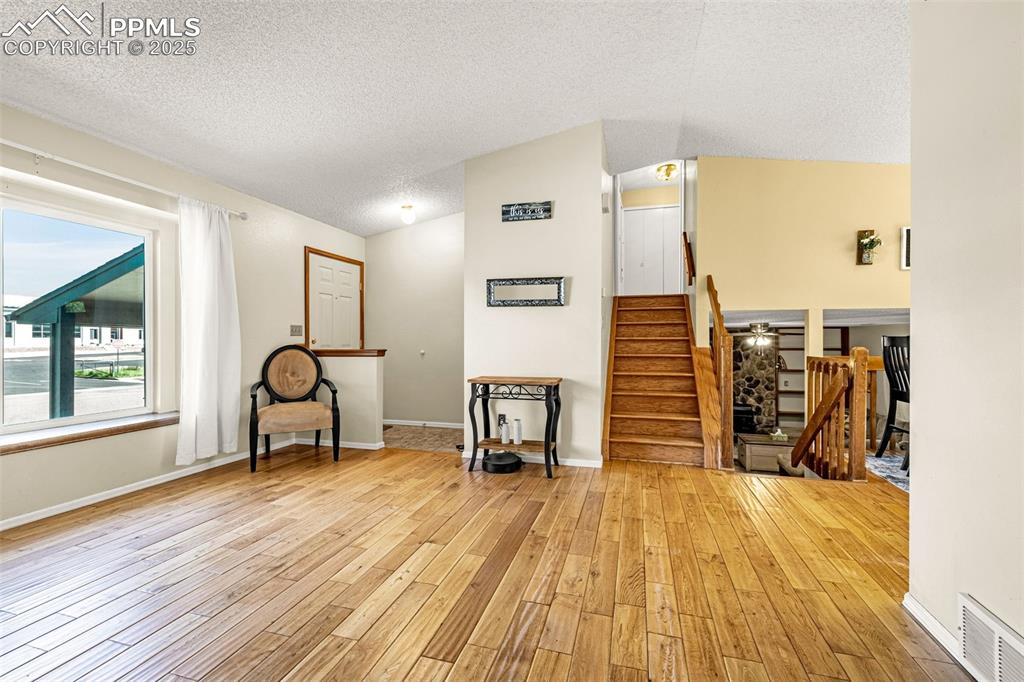 Image 7 of 37: Unfurnished room with stairs, a textured ceiling, light wood-style flooring