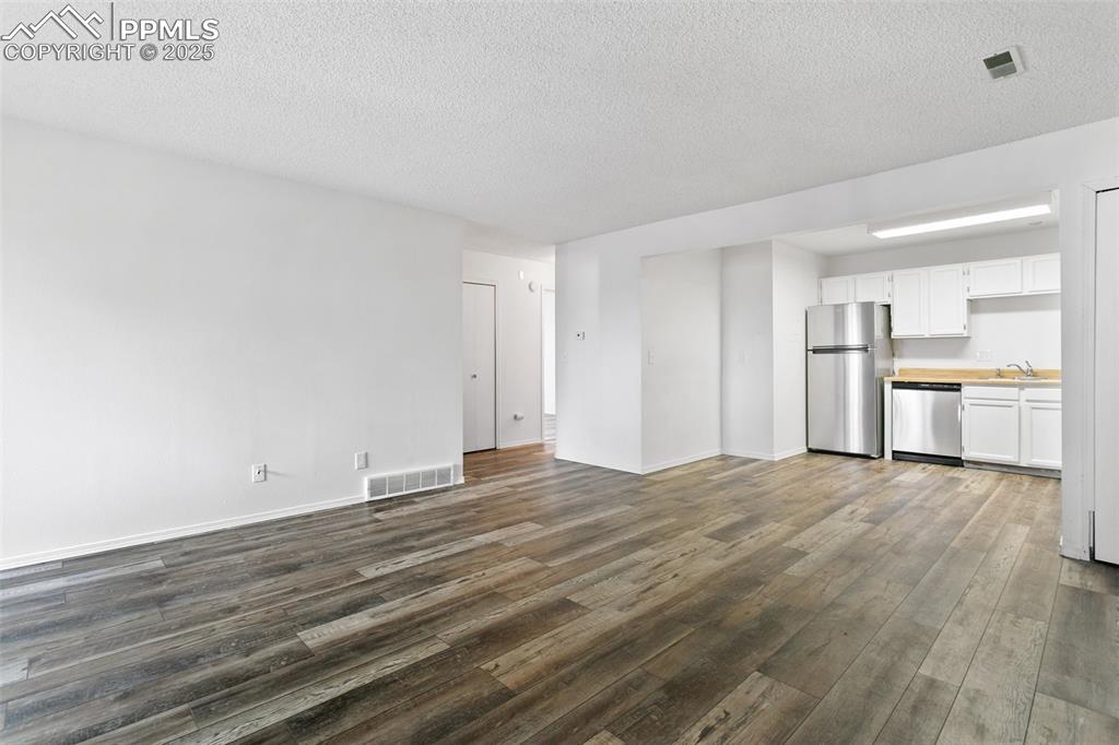 Image 3 of 30: Unfurnished living room featuring baseboards, visible vents, dark wood fini