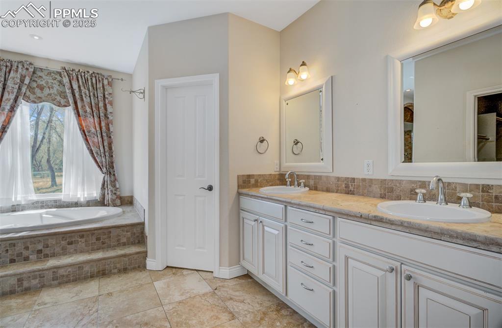 Image 15 of 48: Primary bathroom highlighting the dual vanity and soaking tub