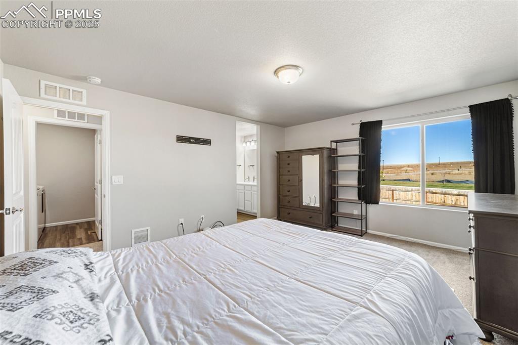 Image 10 of 23: Bright, spacious primary suite with neutral tones and plenty of natural lig