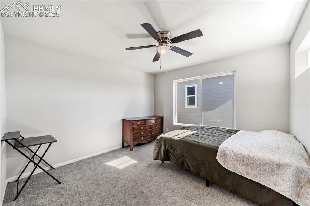 Image 13 of 23: Comfortable secondary bedroom with ceiling fan and bright windows.