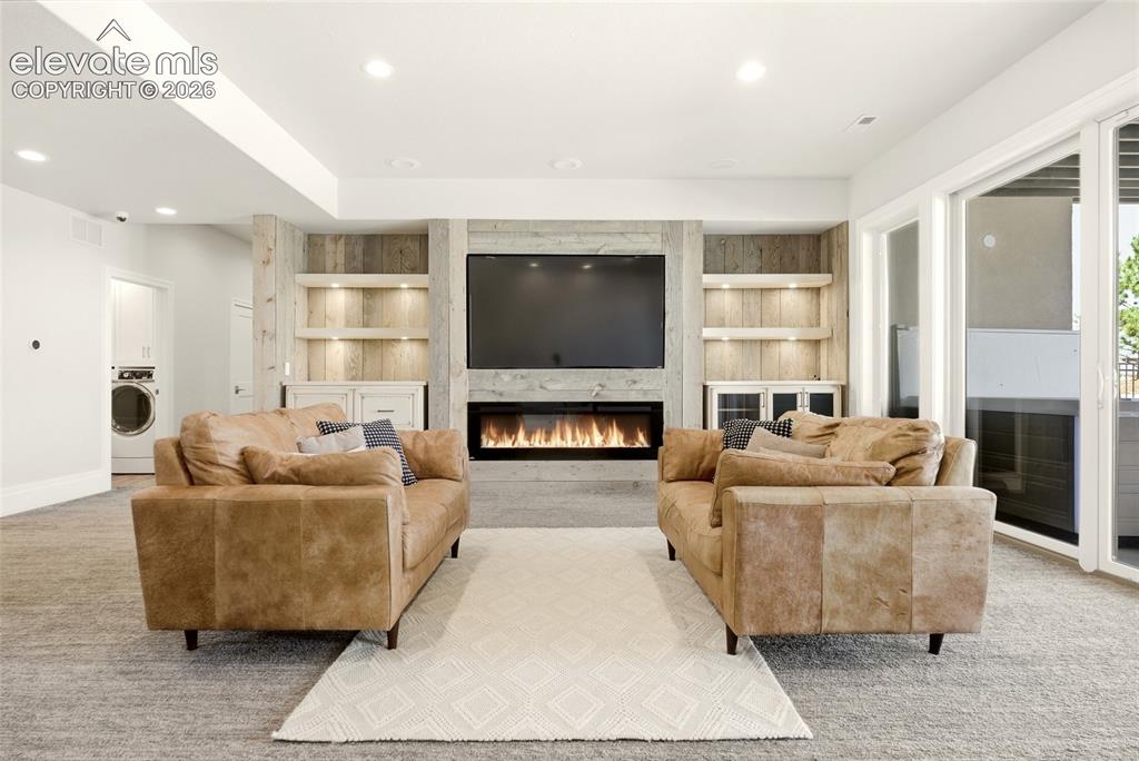 Image 25 of 50: Contemporary living area featuring a built-in electric fireplace, integrate