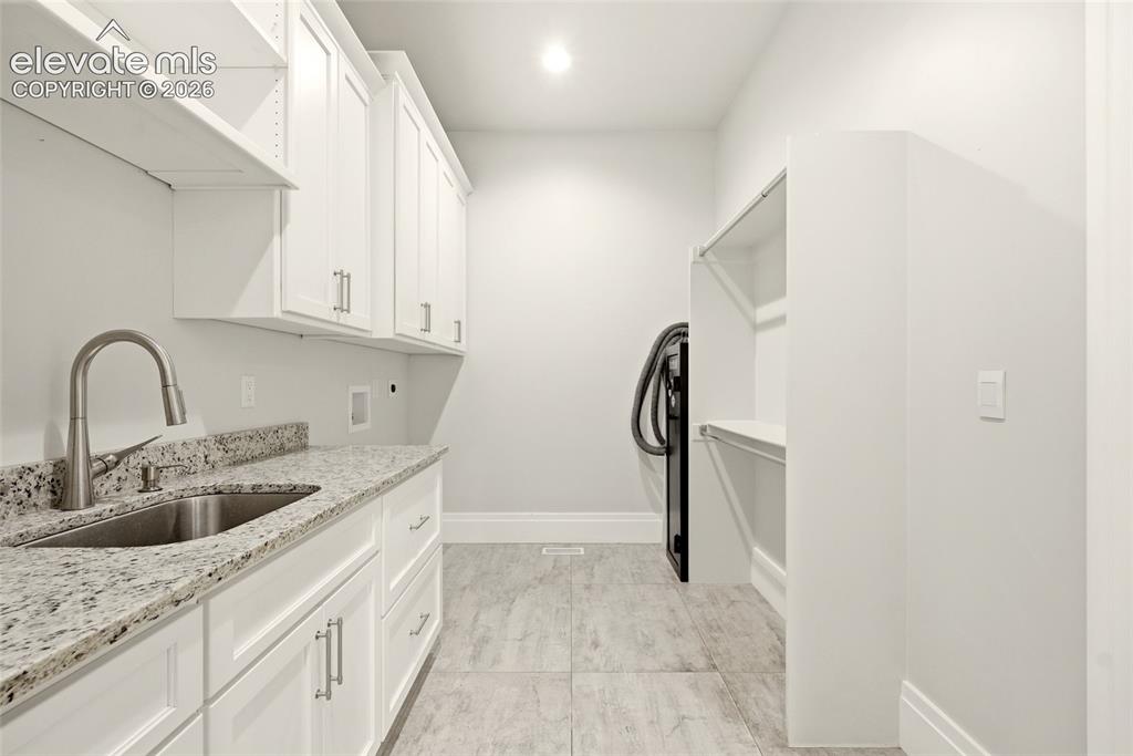 Image 29 of 50: Utility room featuring white cabinetry, a stainless steel sink with a goose