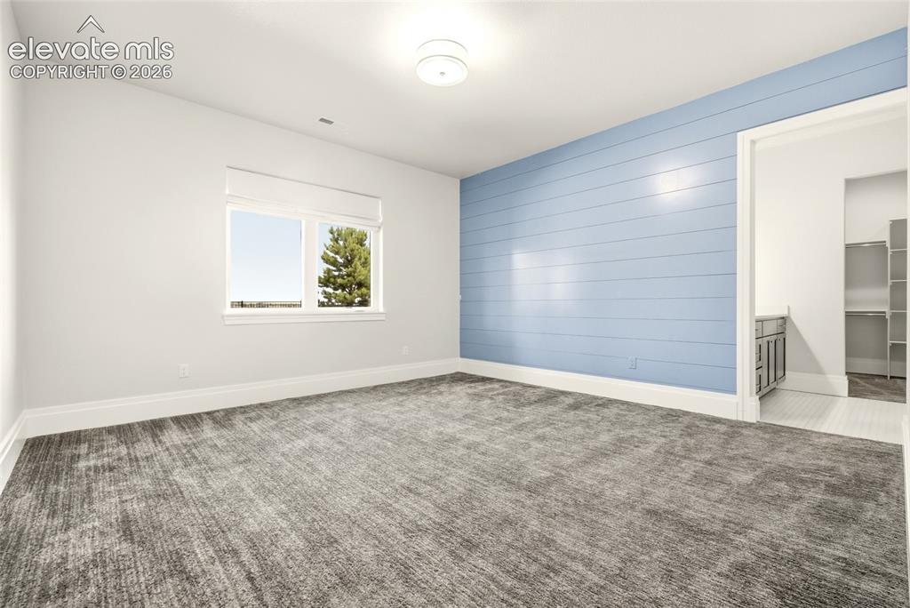 Image 34 of 50: Spacious room featuring a light blue shiplap accent wall, patterned grey ca