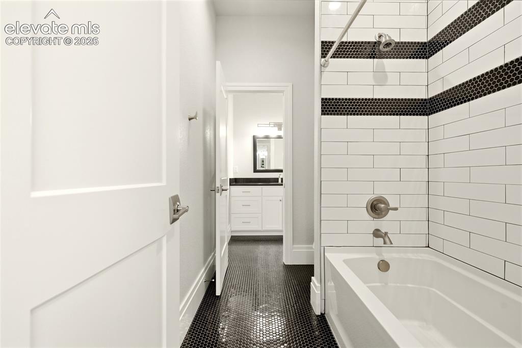 Image 37 of 50: Bathroom featuring a soaking tub with subway tile surround and dark penny t