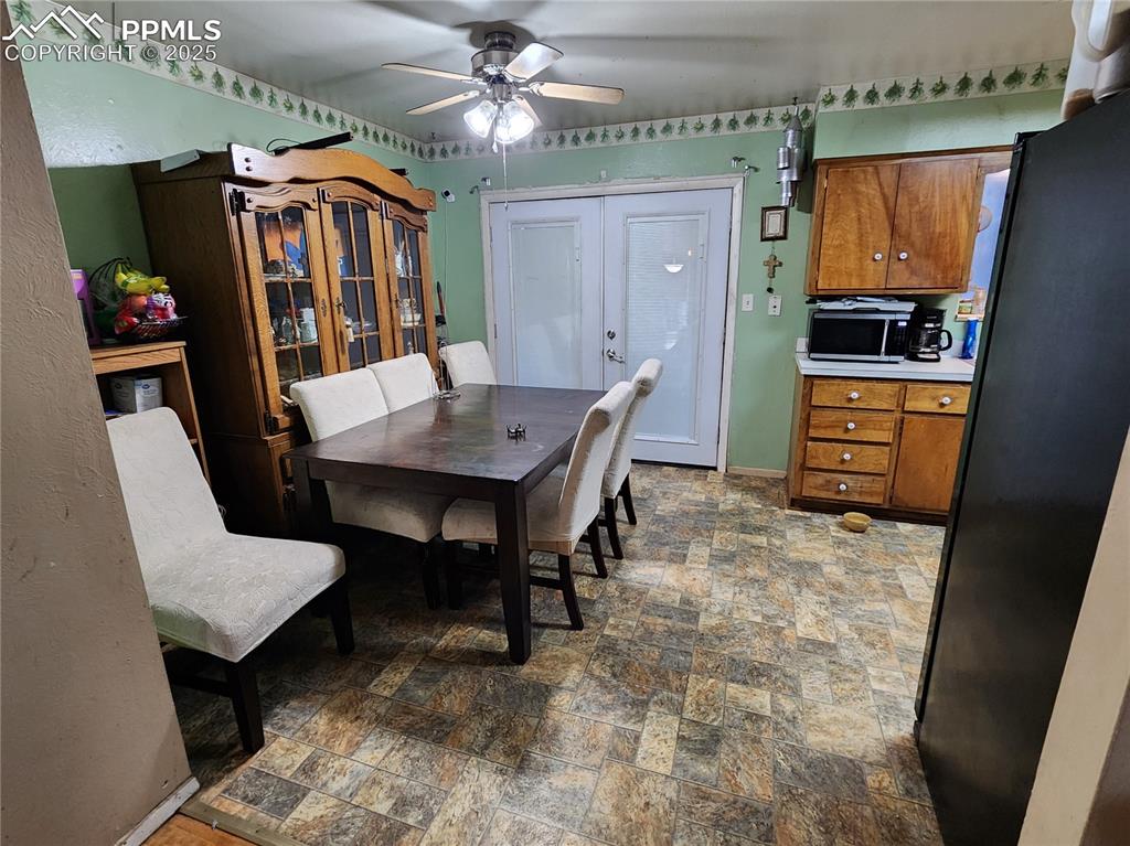 Image 10 of 33: Dining room with stone finish floors, french doors, and a ceiling fan